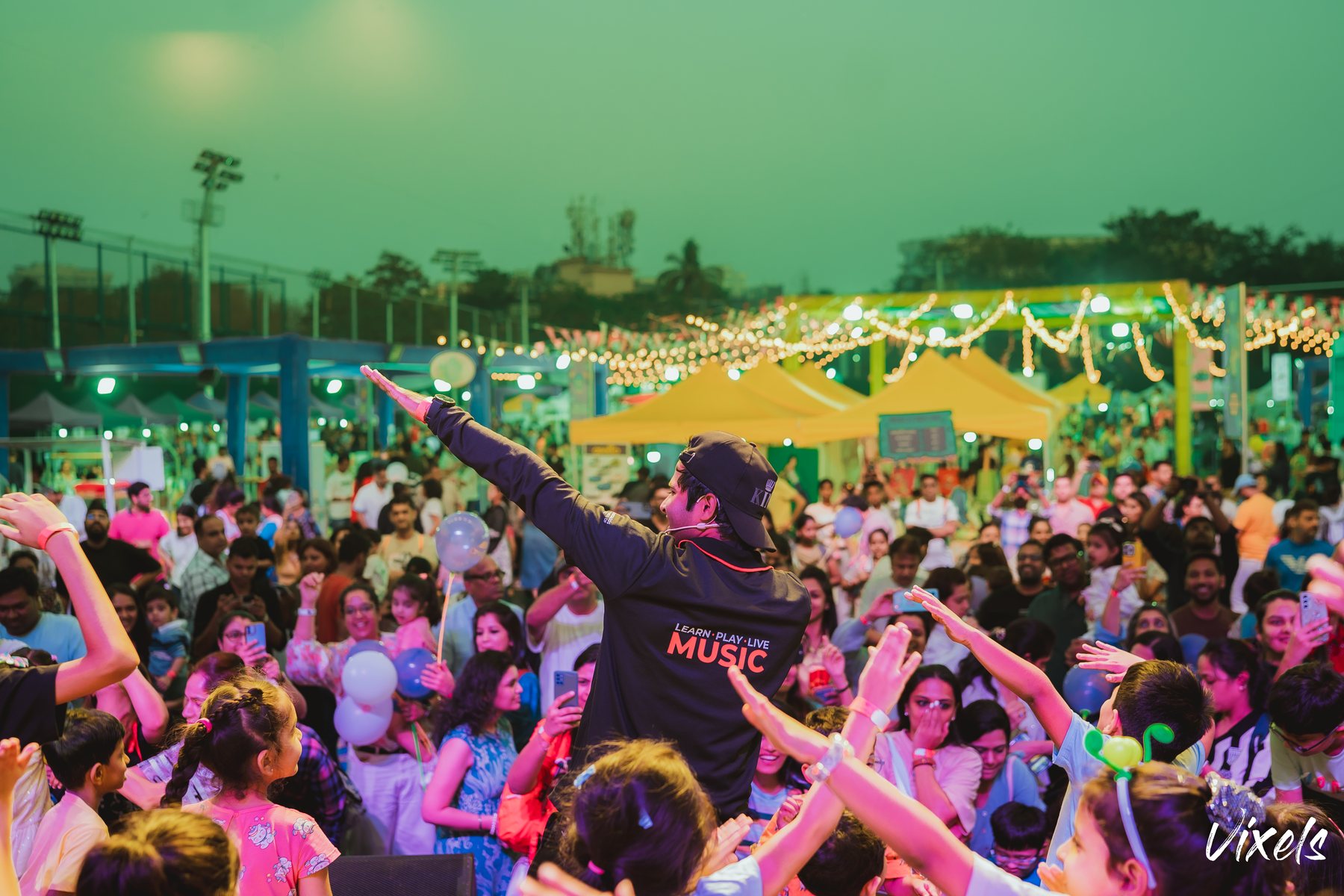 The crowd at Frolic Fields under evening string lights
